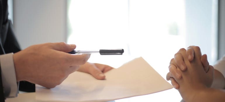 person handing a contract to a woman.