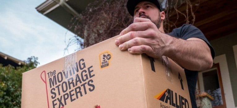 Professional packer from Hendra Moving and Storage carrying a box.