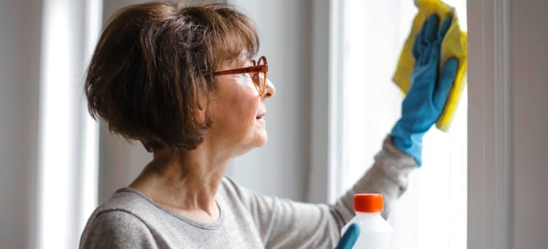 Older woman cleaning the windows.