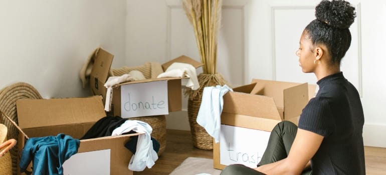 Woman deciding what to throw away, donate or keep in order to organize kids' toys before relocation.