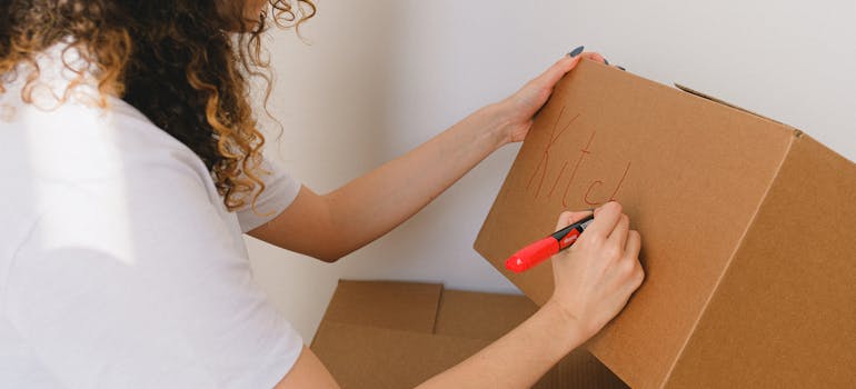 Woman labeling a box in order to avoid one of the most common moving mistakes businesses make when relocating.