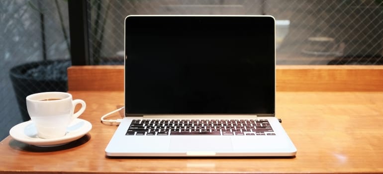Picture of a laptop next to a cup of coffee 