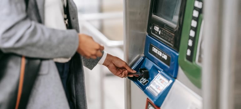 Faceless woman inserting credit card into subway ticket machine