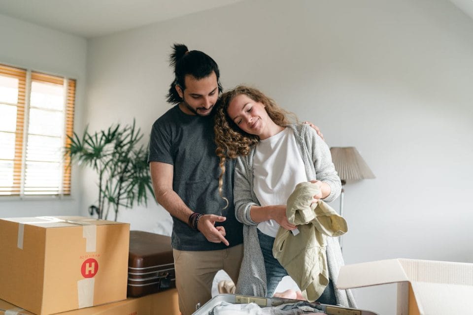 couple bonding and unpacking suitcase in new home