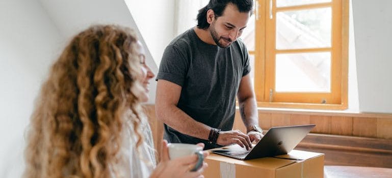 couple using laptop on carton box