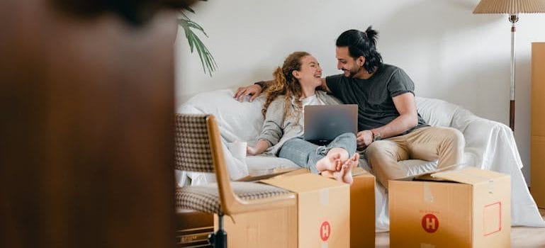 couple with laptop sitting on couch in new house after a Stress-Free Move