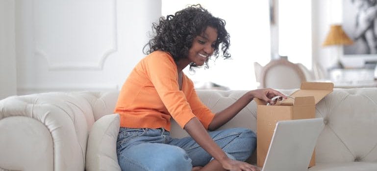 woman opening box and using laptop