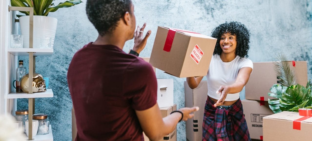 Woman Throwing Moving Box to Friend