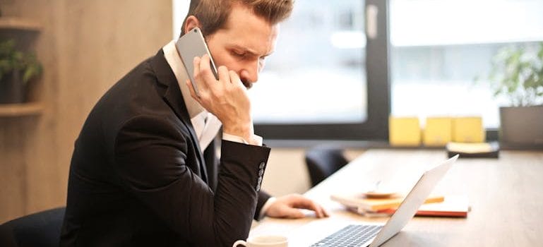 Man Having a Phone Call In-front of a Laptop
