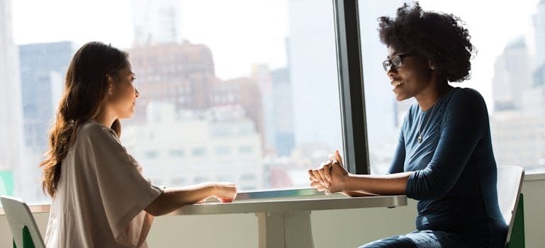 Two Women Sitting on Chairs Beside Window