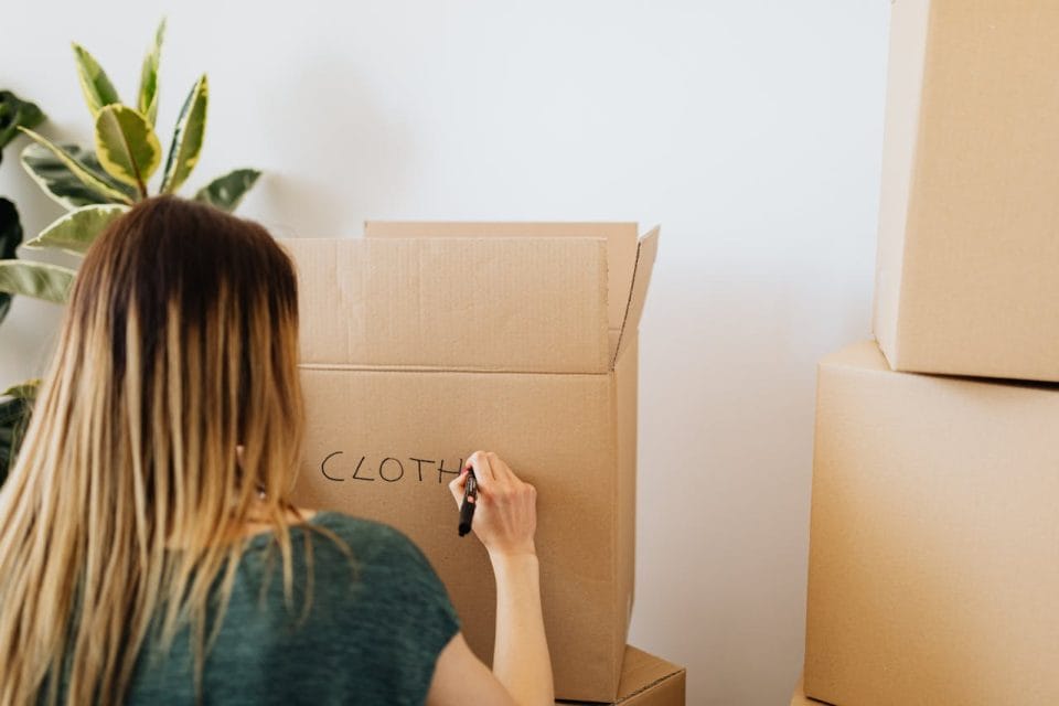 Woman packing stuff and writing on carton box