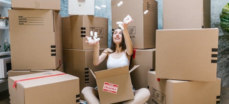 Woman in Black Tank Top Sitting on Brown Cardboard Box