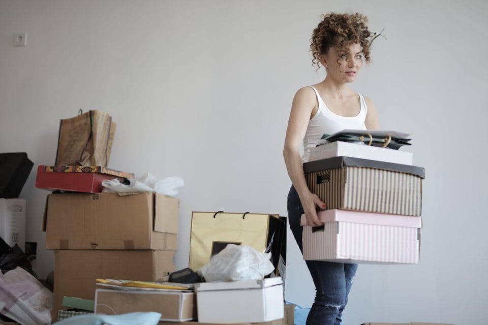 woman carrying stack of cardboard boxes for relocation