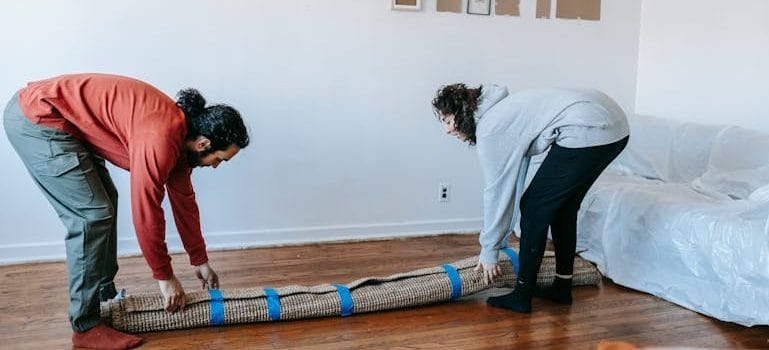 Couple Lifting A Rolled Carpet