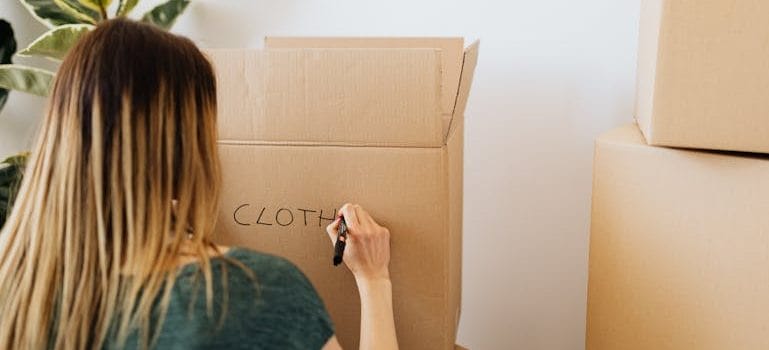 Woman packing stuff and writing on carton box