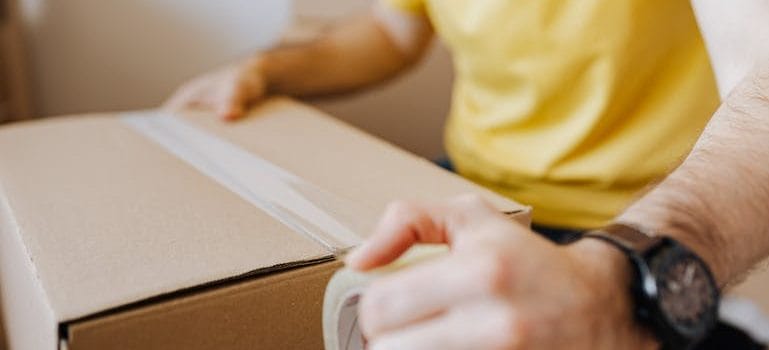 man sealing carton box with tape