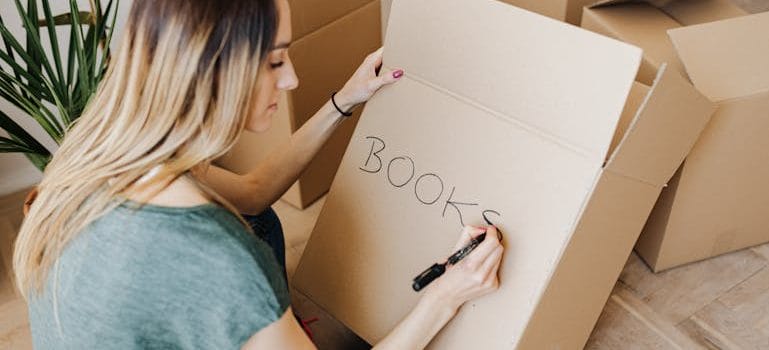 woman writing on cardboard container 