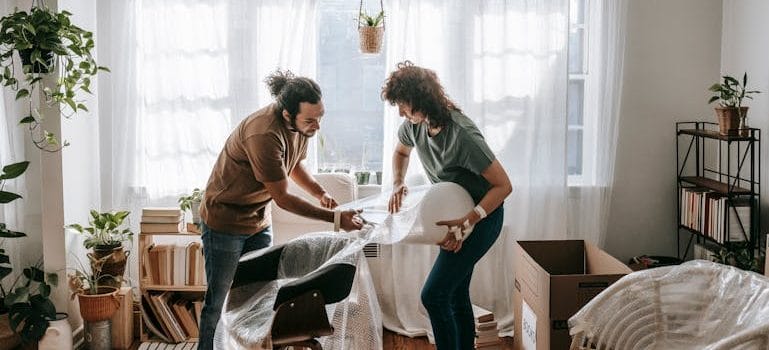 Couple Putting Bubble Wrapping On Chairs