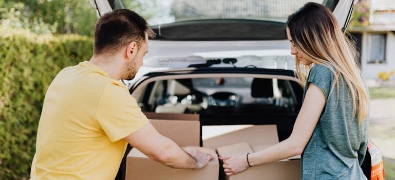 couple putting carton boxes into car trunk