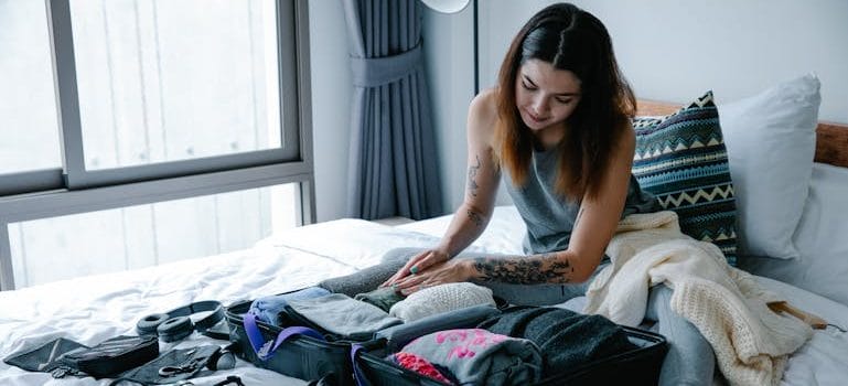 Woman Sitting on Bed at Home Packing Suitcase