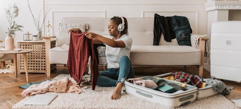 A Woman Listening on Her Headphones while Packing