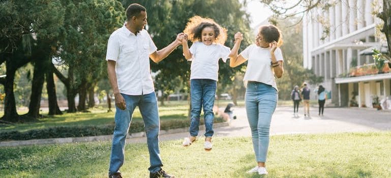 A Man and a Woman Assisting a Girl While Jumping